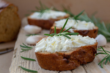 Sliced bread with light cheese on a wooden board.