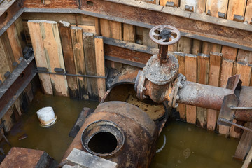 rusty pipe with a crane in the pit. repair of water supply