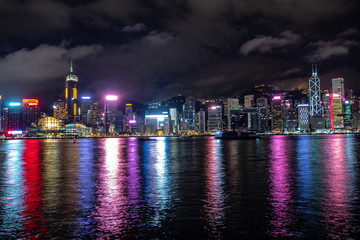 Naklejka premium Beautiful panorama scene of hong kong city midtown at night with skyscrapers illuminated reflecting in the river for background