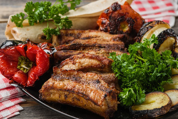 The meat and vegetables roasted on a grill with fresh greens   black plate in style  rustic