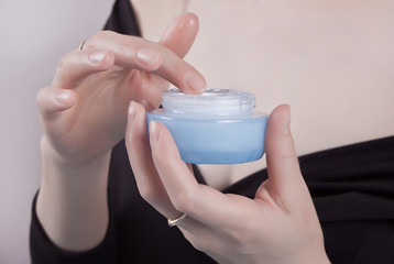 Beautiful hands of young woman are with cosmetic cream container