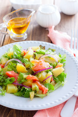 Potato salad with salmon on a white plate, selective focus
