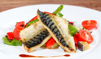 Mackerel baked with lemon, cherry tomatoes, vegetables and spices.