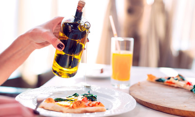 The girl pours oil Pizza.