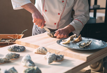 Opening the hollow and flat oysters. Chef opens oysters in the restaurant.