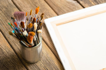 bundle of  paintbrush at tin can, artist canvas, rusty wooden