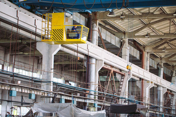 The girl working in the cab of a crane. Heavy industry, metal factory.