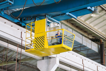 The girl working in the cab of a crane. Heavy industry, metal factory.