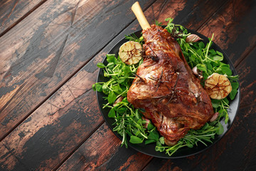 Roast Lamb leg with rosemary and garlic. on black plate, wooden table