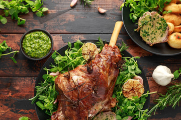 Roast Lamb leg with mint sauce, rosemary and garlic. on black plate, wooden table © grinchh
