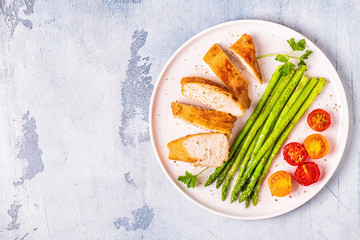 Roasted chicken breast with asparagus and tomatoes.