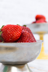 Bright ripe strawberry in a metal cups on a light background.