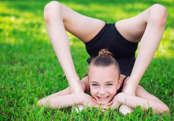 Beautiful little girl doing gymnastics on the grass on a sunny day