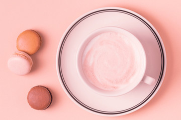 Cup of coffee with macaroons on pastel background.