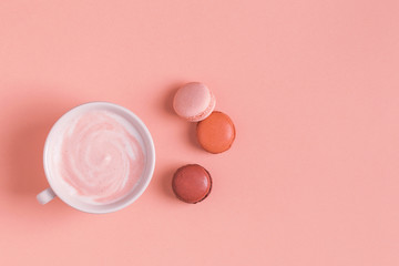 Cup of coffee with macaroons on pastel background.