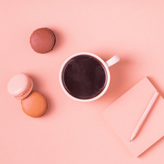 Cup of coffee with macaroons on pastel background.