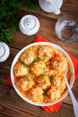 Meatballs with rice in tomato-sour cream sauce on a wooden table, top view, selective focus