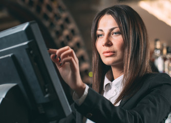 small business, people and service concept - happy woman or waiter or manager in apron at counter with cashbox working at bar or coffee shop