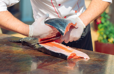 The chef cuts the salmon on the table.