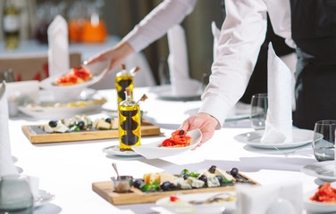 Waiter serving table in the restaurant preparing to receive guests.