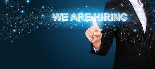 WE ARE HIRING concept with Hand of business pressing a button WE ARE HIRING