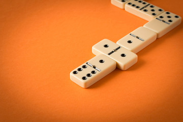Playing dominoes on a orange table. Domino effect.