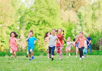 Many different kids, boys and girls running in the park on sunny summer day in casual clothes - obrazy, fototapety, plakaty