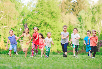Obraz premium Many different kids, boys and girls running in the park on sunny summer day in casual clothes