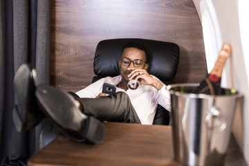 Successful young Afro American black businessman sitting in the chair of his private jet