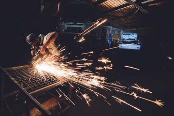 The employee of the service station produces body repair with a welding machine in hand sparks