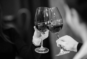 Man and woman drinking red wine. In the picture, close-up hands with glasses.