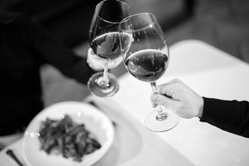 Man and woman drinking red wine. In the picture, close-up hands with glasses.