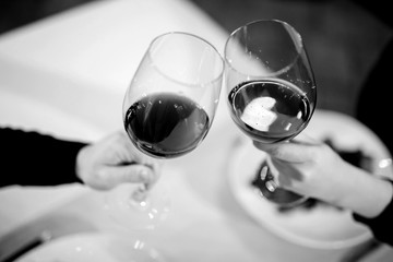 Man and woman drinking red wine. In the picture, close-up hands with glasses.