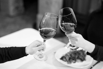 Man and woman drinking red wine. In the picture, close-up hands with glasses.
