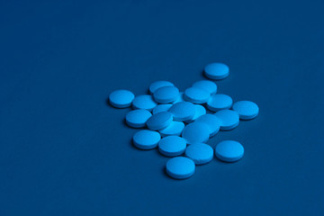 White pills with blue neon lights closeup