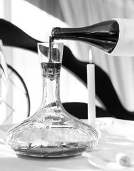 A sommelier pouring red wine into decanter