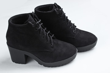 Black suede boots on gray background.