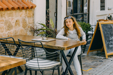 Young beautiful girl sitting in a street cafe in old city of Antalya