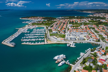 Fototapeta premium Aerial view of city of Zadar. Summer time in Dalmatia region of Croatia. Coastline and turquoise water and blue sky with clouds. Photo made by drone from above.