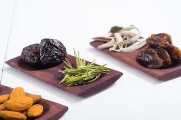 dried fruits and spices on wooden tray, white table