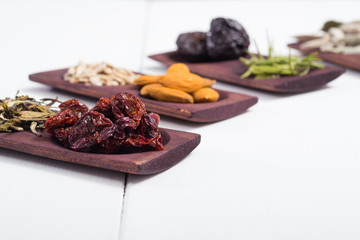 dried fruits and spices on wooden tray, white table