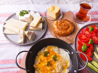 Traditional Turkish breakfast - fried eggs, fresh vegetables, olives, cheese, cake and tea