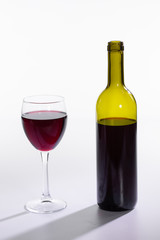 Bottle and glass with red wine on white background