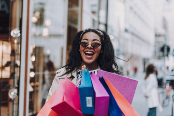 Happy afro american girl with shopping bags standing on the street