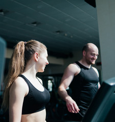 Fototapeta na wymiar Cheerful Couple doing cardio exercise on a treadmill.