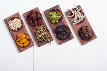 dried fruits and spices on wooden tray, white table