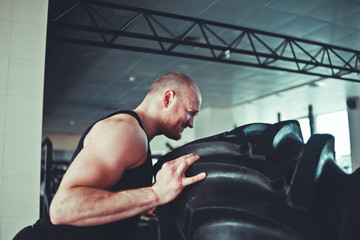 Strong man picks up a big heavy rubber wheel. Functional training