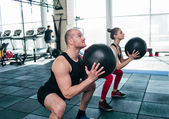 Сouple functional training. Sporty man and fit woman do exercise with medicine ball in gym