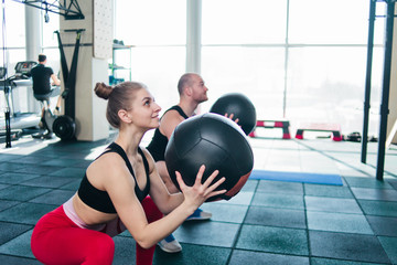 Сouple functional training. Sporty man and fit woman do exercise with medicine ball in gym
