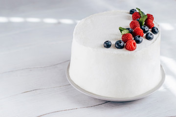 Obraz na płótnie Canvas White cake decorated with raspberries and blueberry